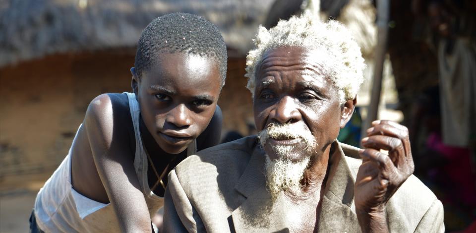 © CBM/Tobias Pflanz. Albert (74) is blind due to onchocerciasis. Here with his grandson Marceil (7).